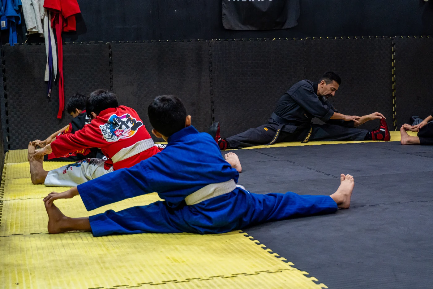 Alumnos y profesor realizando estiramientos sobre el tatami de Alkano