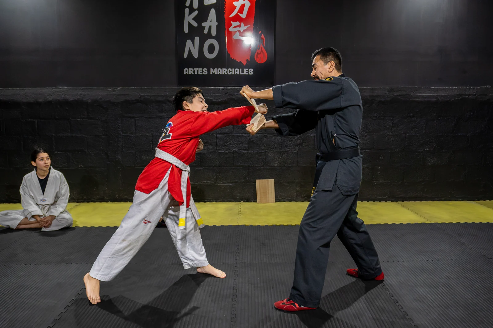 Alumno realizando un ejercicio de Taekwondo guiado por su profesor